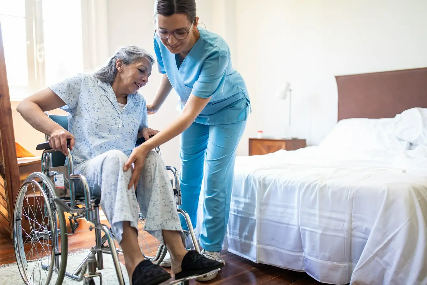 pielęgniarka pomaga seniorce na wózku